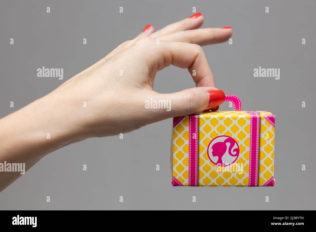 Weibliche Hand, die einen Koffer aus Spielzeugkarton hält Stockfoto