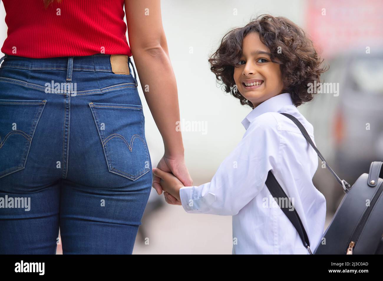 Porträt eines Schuljungen, der die Hand hält und lächelnd zurückblickt Stockfoto