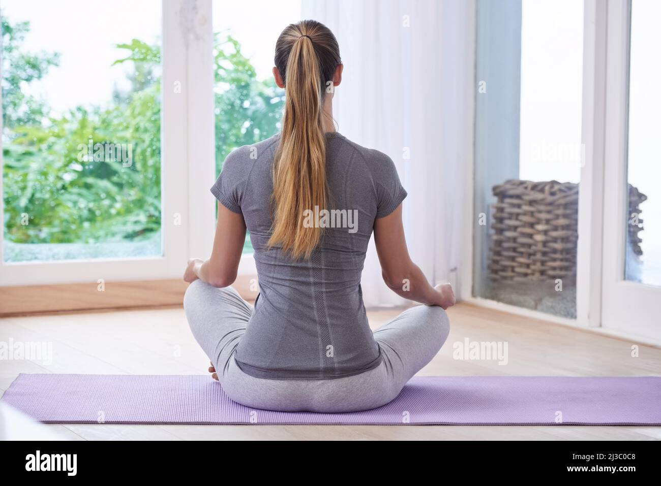 Behalte dich ruhig und mache Yoga. Eine junge Frau, die zu Hause meditiert. Stockfoto