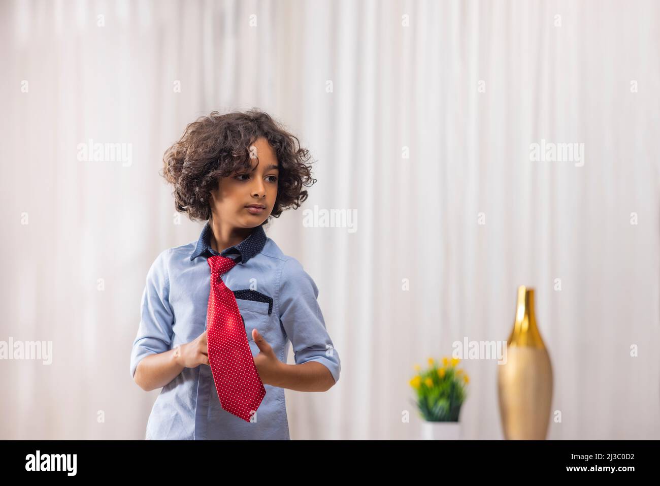 Porträt eines Jungen in roter Krawatte, der im Wohnzimmer steht Stockfoto