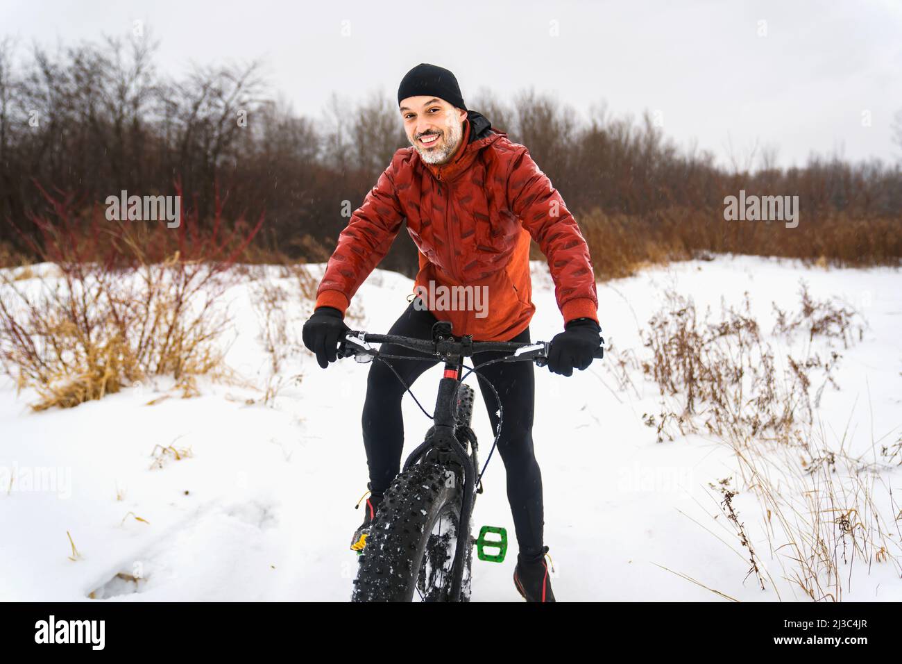 Netter Mann, der im Winter auf einem fetten Fahrrad fährt Stockfoto