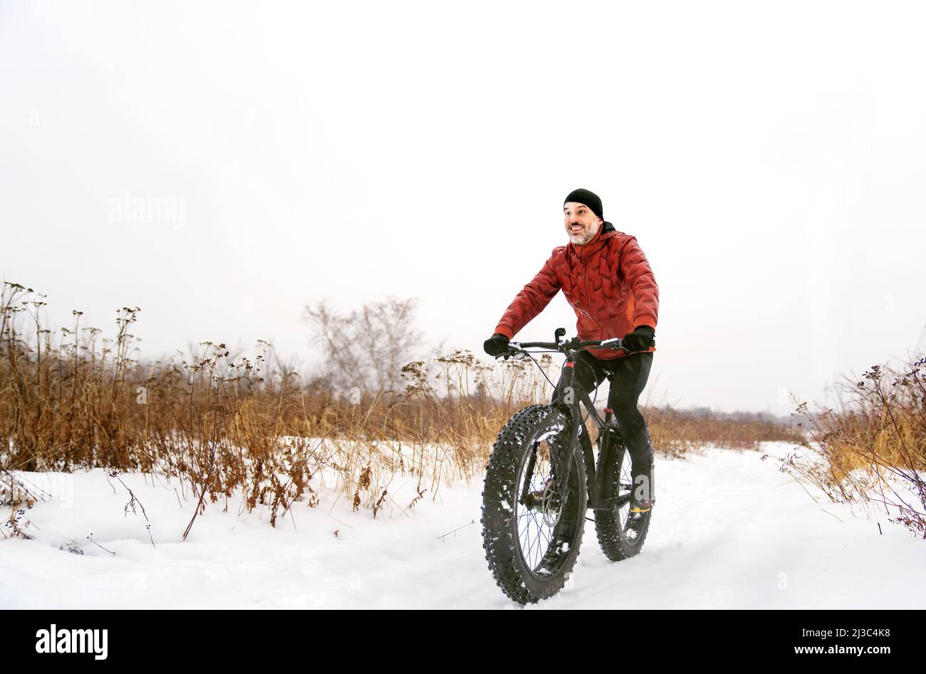 Netter Mann, der im Winter auf einem fetten Fahrrad fährt Stockfoto