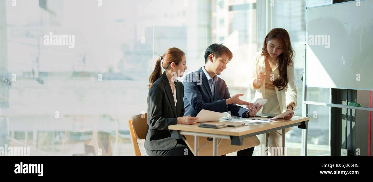 Gruppe von Geschäftsleuten Asiaten arbeiten an Diagramm-Diagramm, sprechen, Planung analysieren Investitionen und Marketing auf Tablet im Büro. Panorama-Aufnahme. Stockfoto