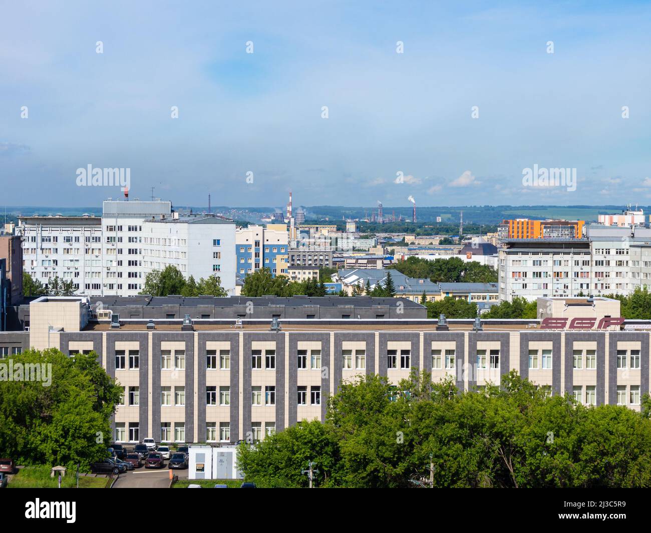Kemerowo, Russland - 24. juni 2021. Stadtlandschaft aus einer Höhe - ein Industriegebiet mit rauchenden Kaminen und einem Wald mit landwirtschaftlichem Boden auf dem h Stockfoto
