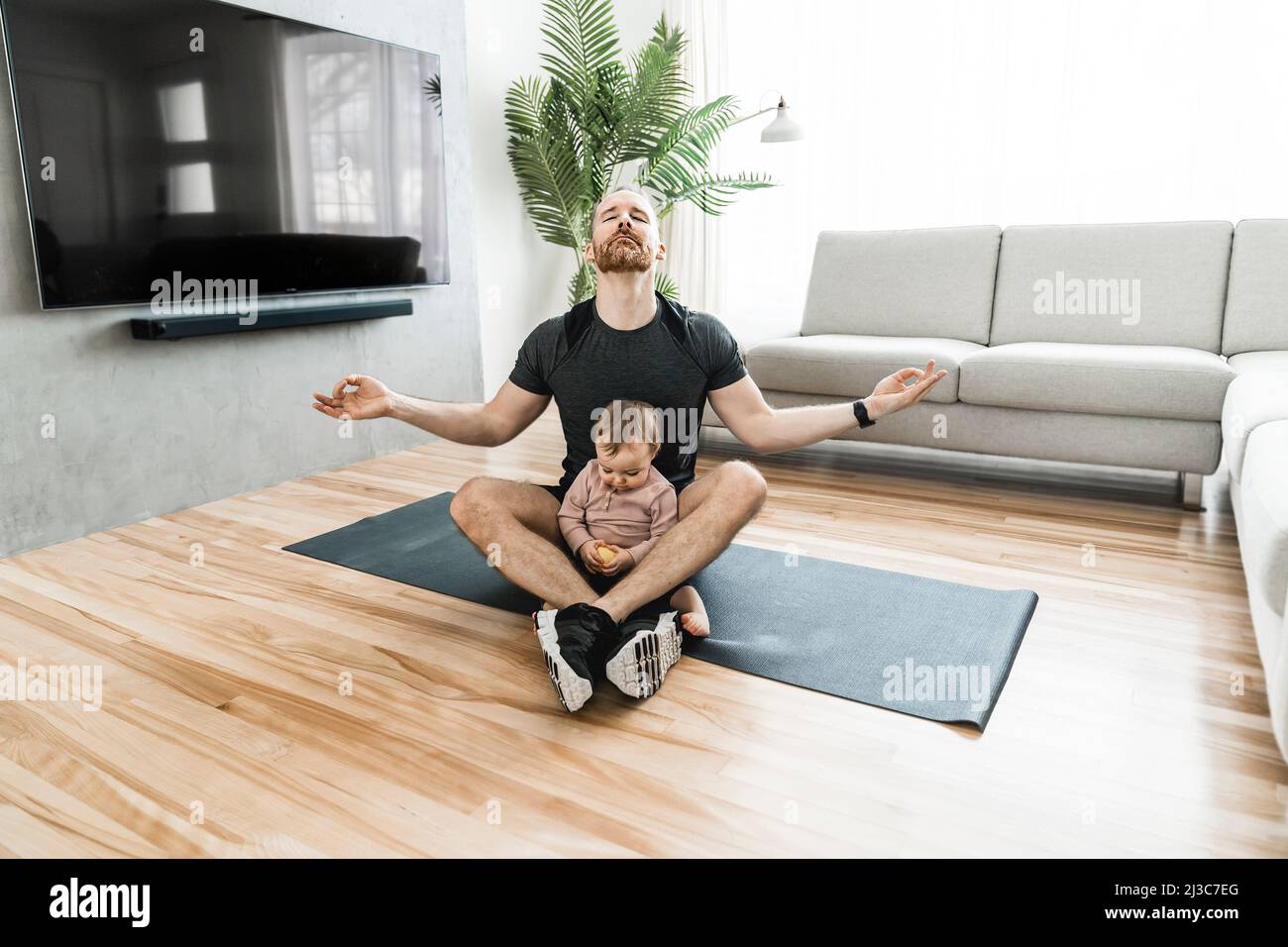 Vater trainiert mit seinem Baby das Baby sieht jemanden an. Stockfoto