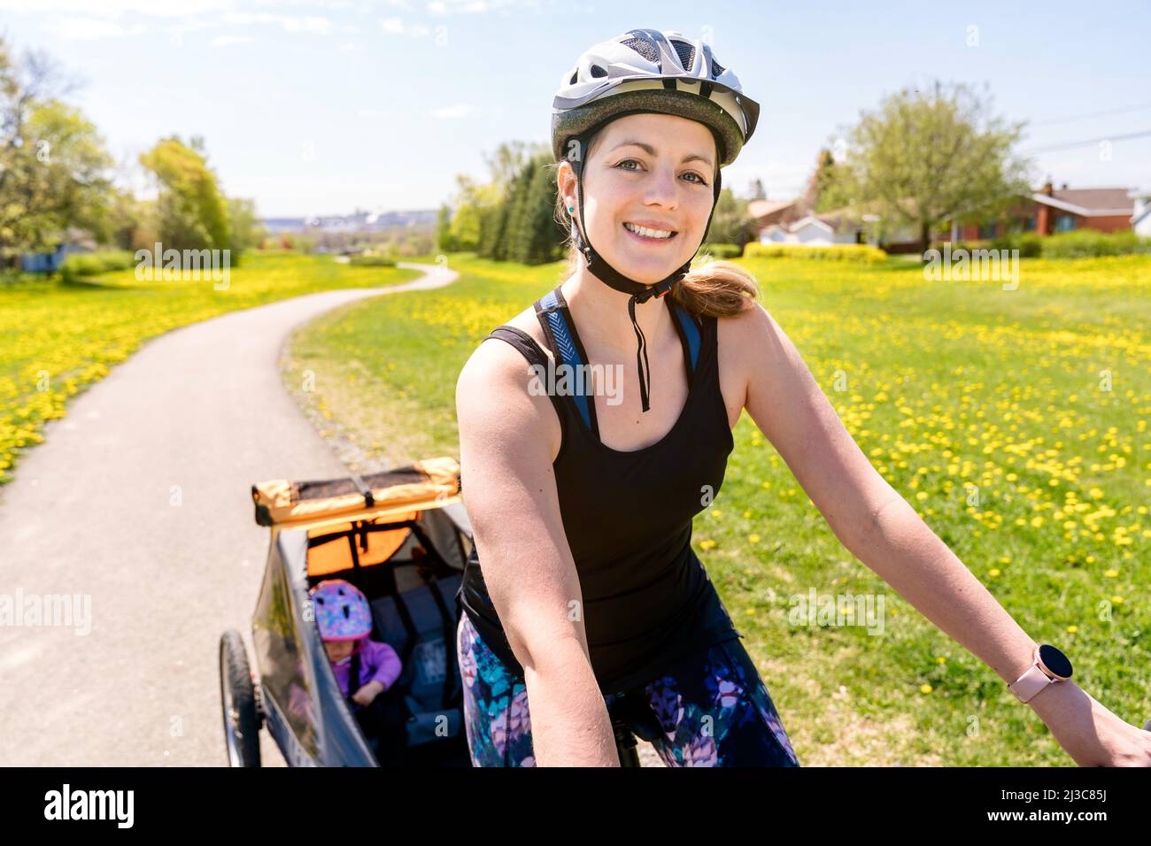 Frau, die mit einem Kinderwagen auf dem Fahrrad unterwegs ist. Stockfoto