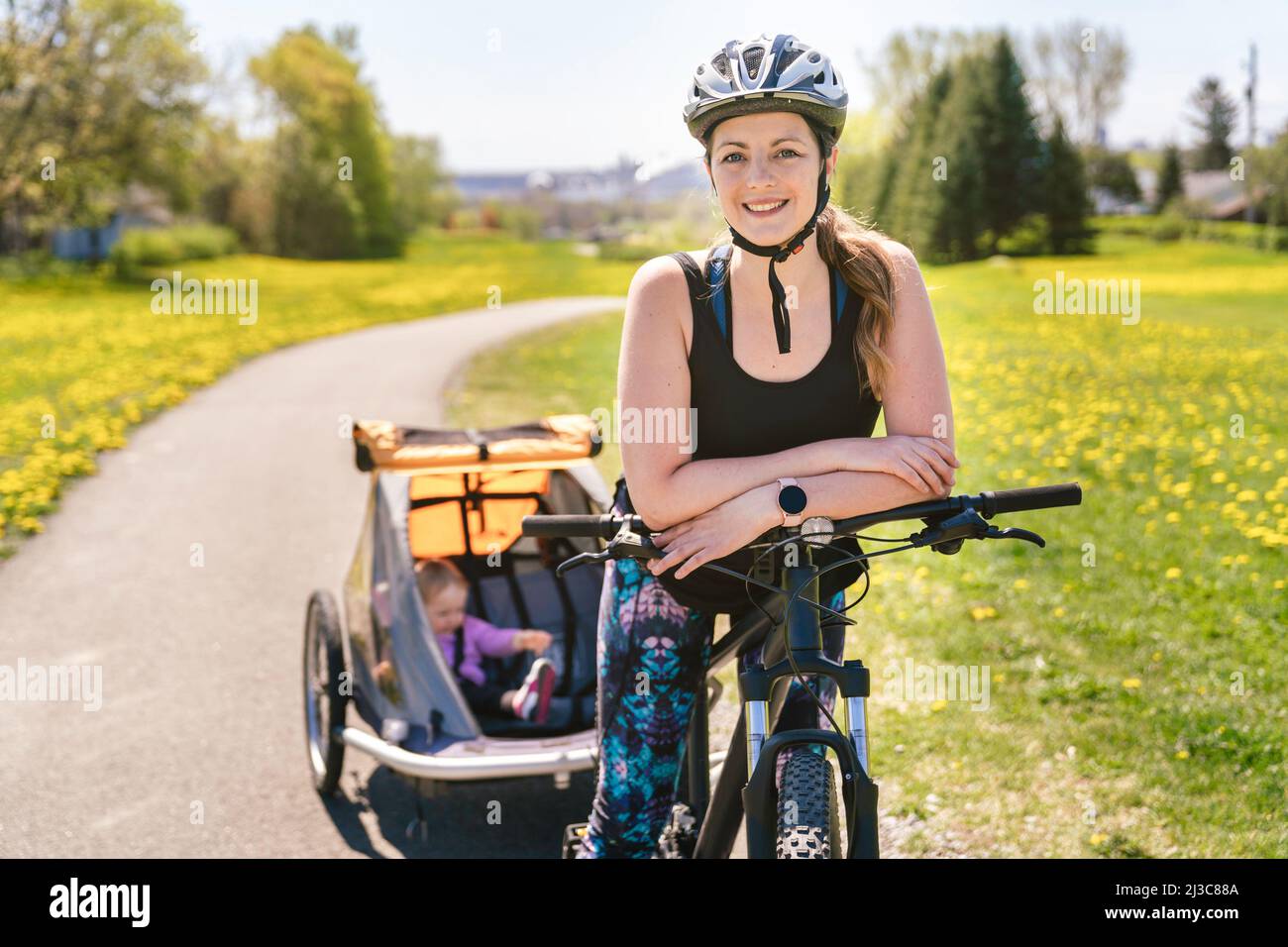 Frau, die mit einem Kinderwagen auf dem Fahrrad unterwegs ist. Stockfoto
