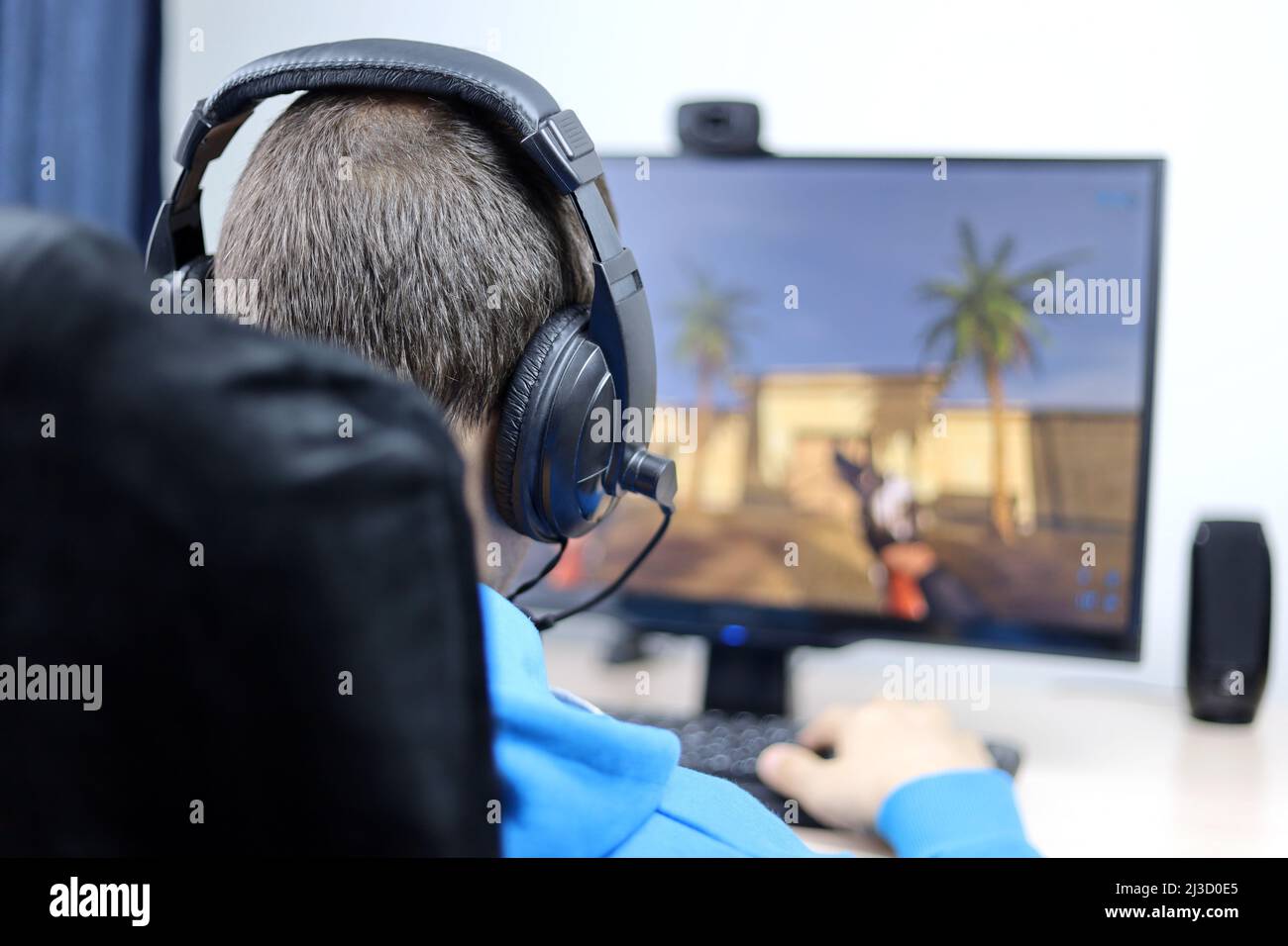 Mann im Headset, der ein Computerspiel auf einem Desktop-PC spielt. Konzept der Spielsucht, Freizeit zu Hause Stockfoto
