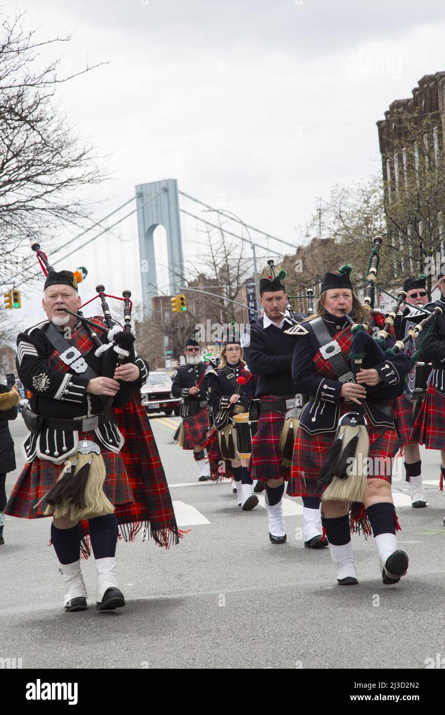 Richmond County Pipes and Drums Band marschieren und treten bei der Saint Patrick's Day Parade in Brooklyn, New York, auf. Turm der Verrazano Brücke im Hintergrund. Stockfoto