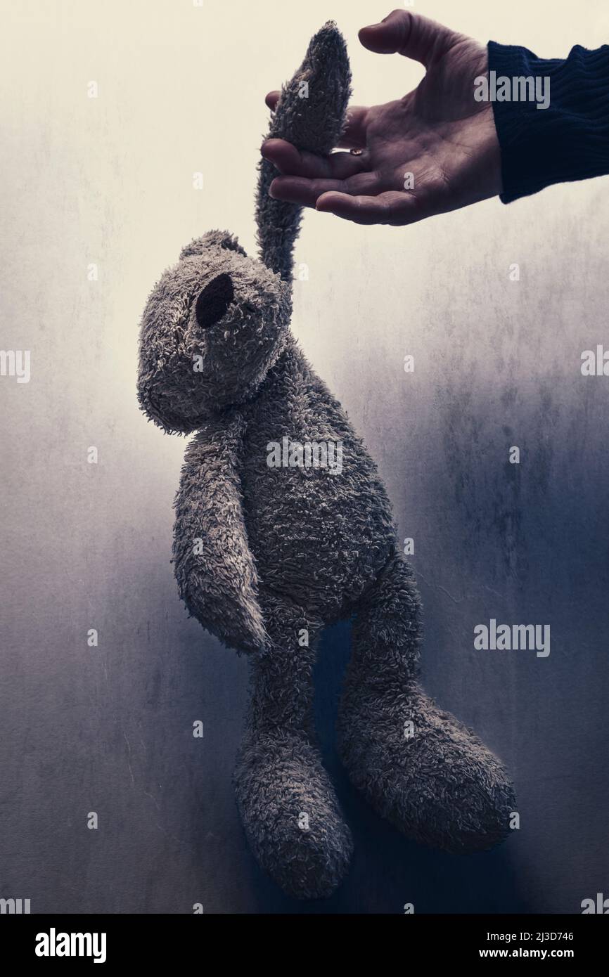 Erwachsene kaukasische Hand, die einen Teddybären loslässt, der Kinder symbolisiert, die aufwachsen. Stockfoto