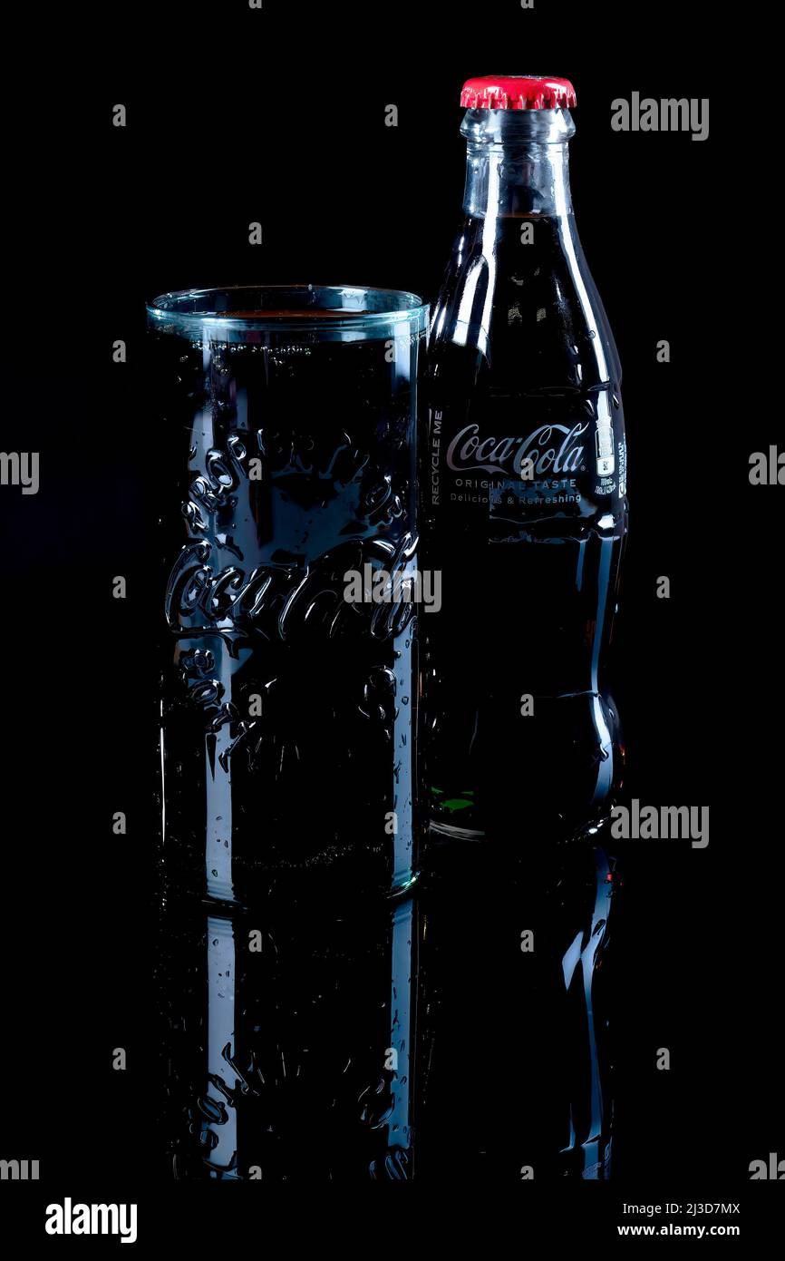 HELSINGBORG, SCHWEDEN - 06. APRIL 2022: Eine Studioaufnahme eines vollen Glases Coca Cola neben der ikonischen Glasflasche. Stockfoto