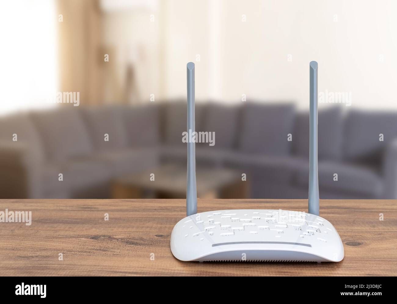 Internet-Router auf Holztisch und verschwommenes Wohnzimmer als Hintergrund. Stockfoto