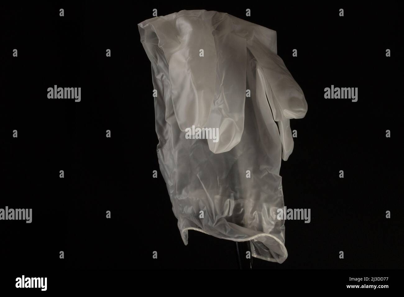 Weißer Einweghandschuh mit einer isolierten Handfläche auf schwarzem Hintergrund Stockfoto