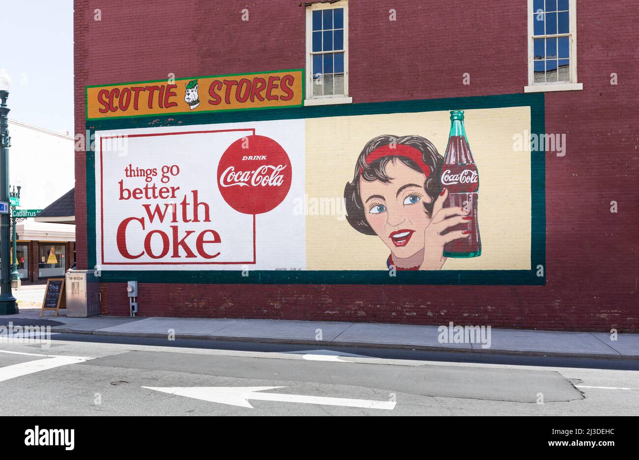 CONCORD, NC, USA-3 APRIL 2022: Ein historisches Coca-Cola-Werbeschild an einer Backsteinmauer, das auch für die Scottie Stores wirbt. Unterzeichnet von Hampton, Stockfoto