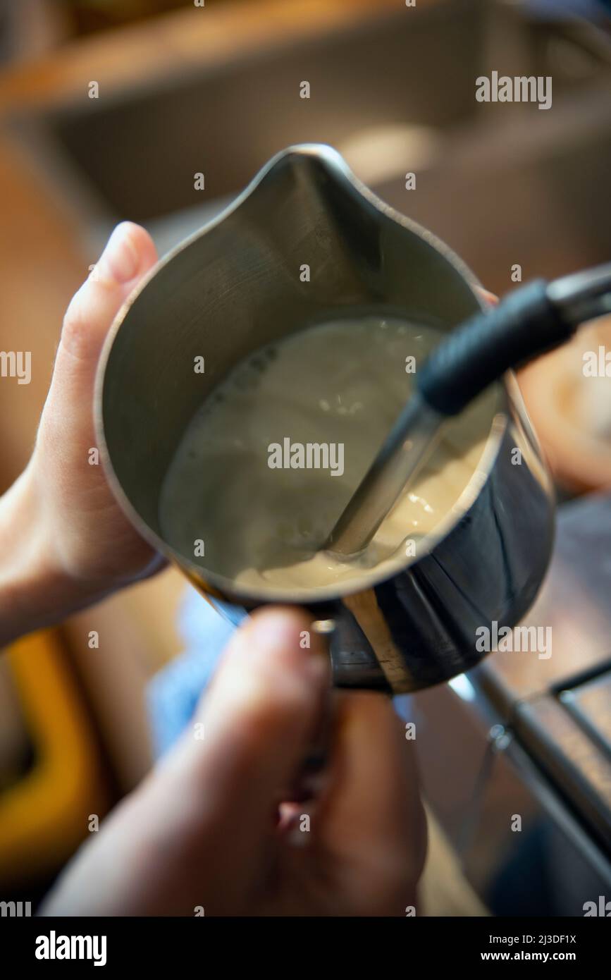 Der Barista texturiert Milch in einem Krug aus Edelstahl Stockfoto