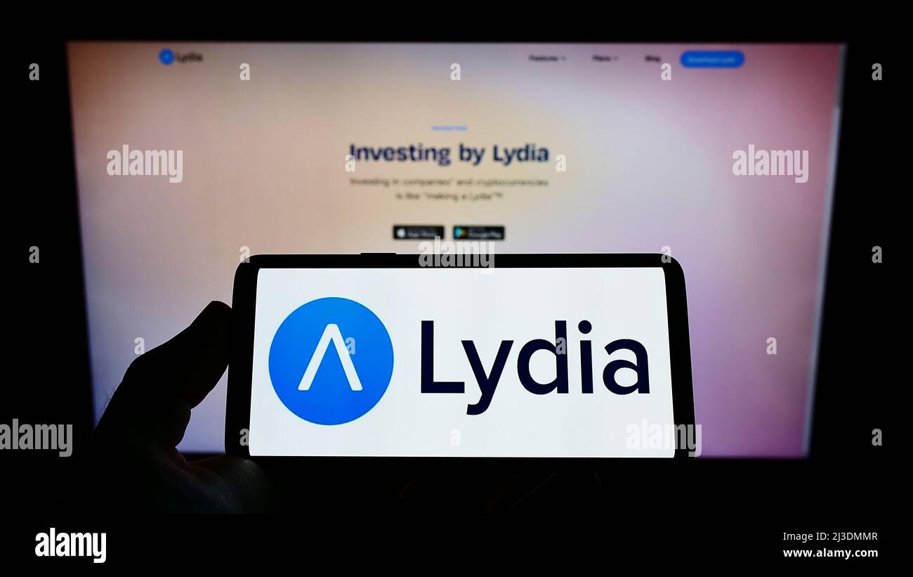 Person mit Mobiltelefon und Logo der französischen Firma Lydia Solutions SAS auf dem Bildschirm vor der Business-Webseite. Konzentrieren Sie sich auf die Telefonanzeige. Stockfoto