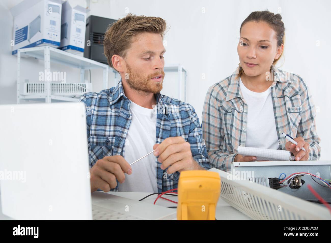 Elektriker, die ein Multimeter zur Diagnose von Heizungsfehlern verwenden Stockfoto