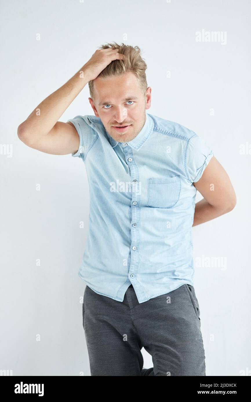 Brutaler Mann in einem Hemd mit kurzen Ärmeln, seine Fäuste geballt, leicht gebeugt, unter dem Blick der Stirn Stockfoto