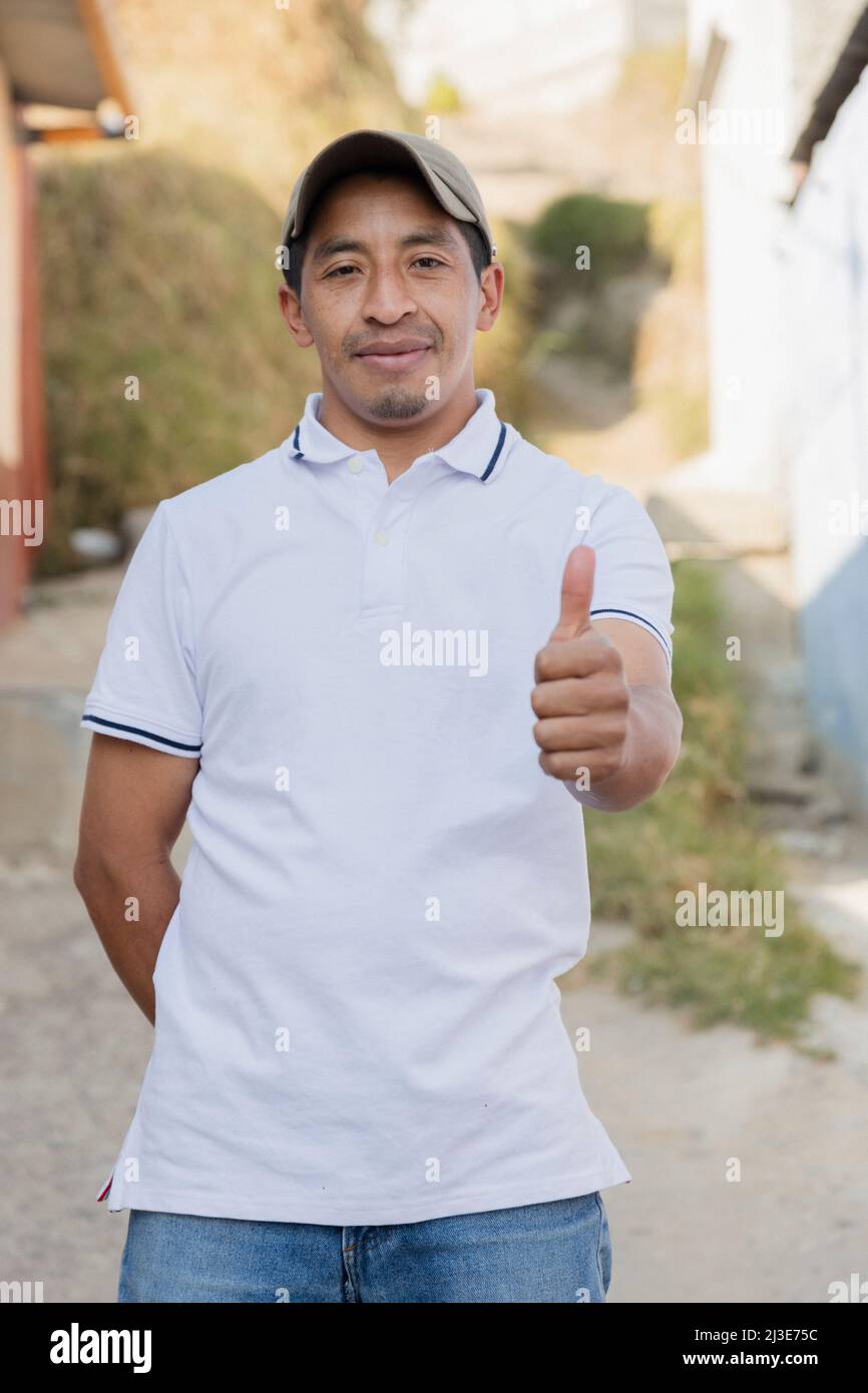 Lateinischer Mann, der vor seinem Haus in ländlicher Umgebung lächelt - stolzer hispanischer Mann, der den Daumen hochgibt Stockfoto