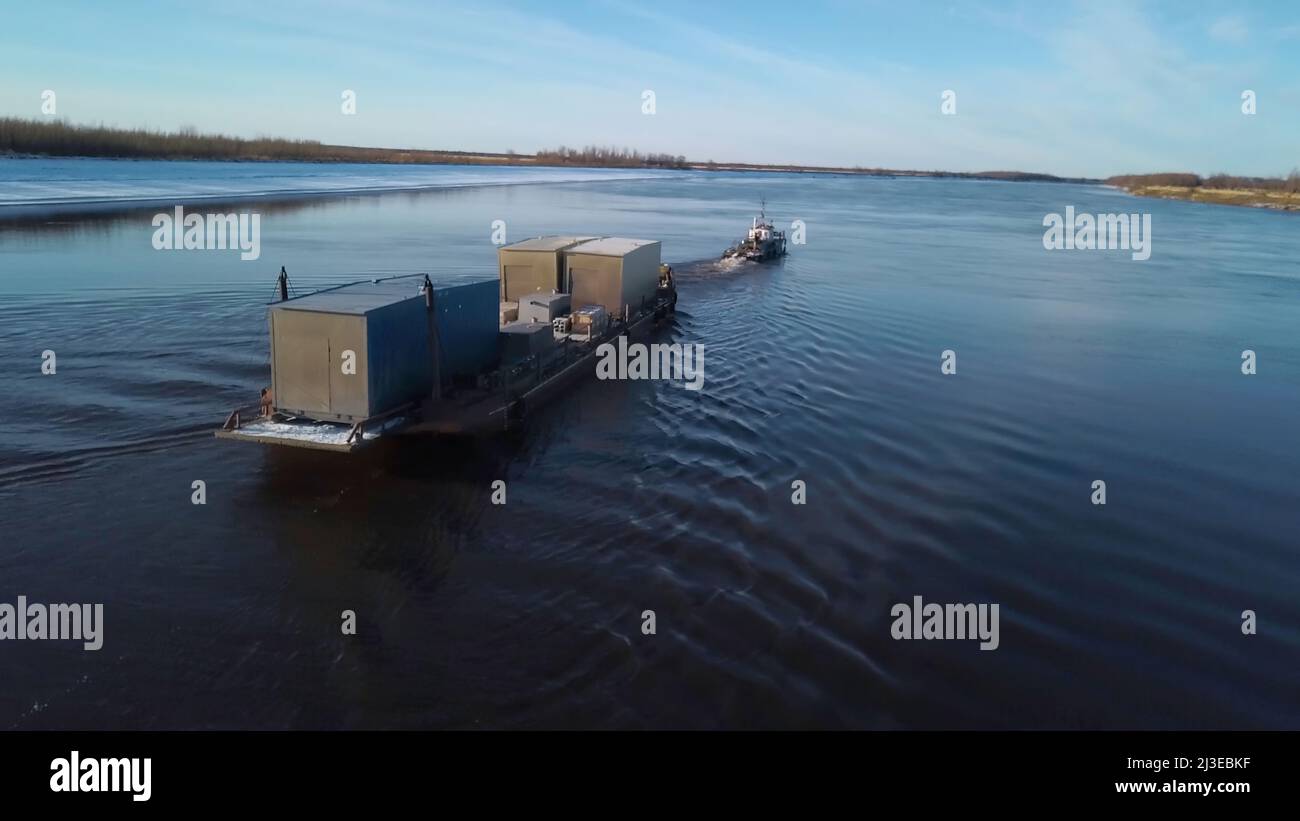 Containerschiff segelt auf einem breiten schönen Fluss auf Sonnenuntergang Himmel Hintergrund. Clip. Konzept des Transports, Luftaufnahme. Stockfoto
