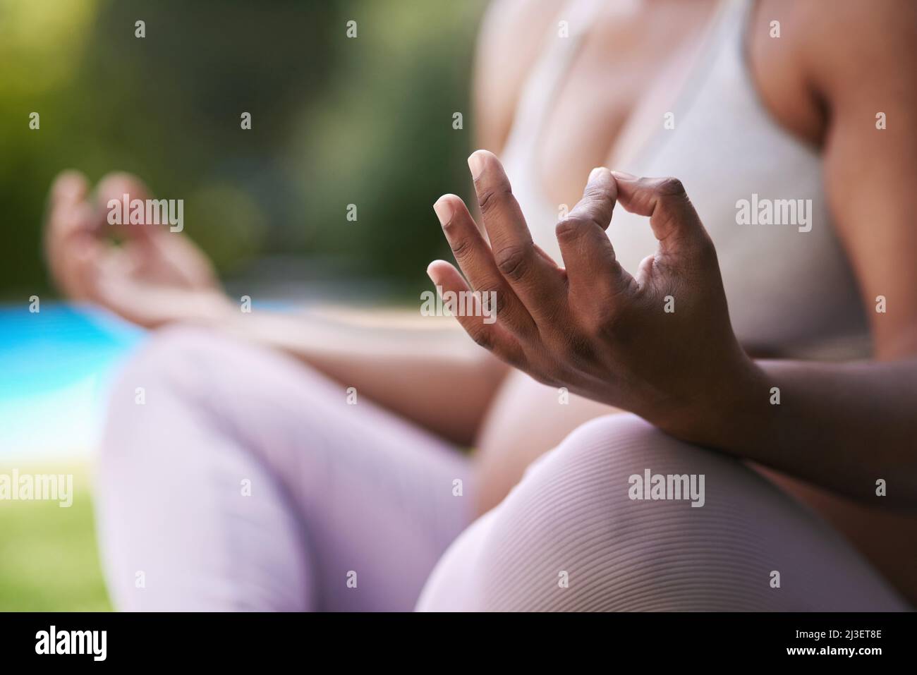 Yoga lehrt dich, tief zu atmen und bewusst zu entspannen. Ausgeschnittene Aufnahme einer Schwangeren, die im Freien meditiert. Stockfoto