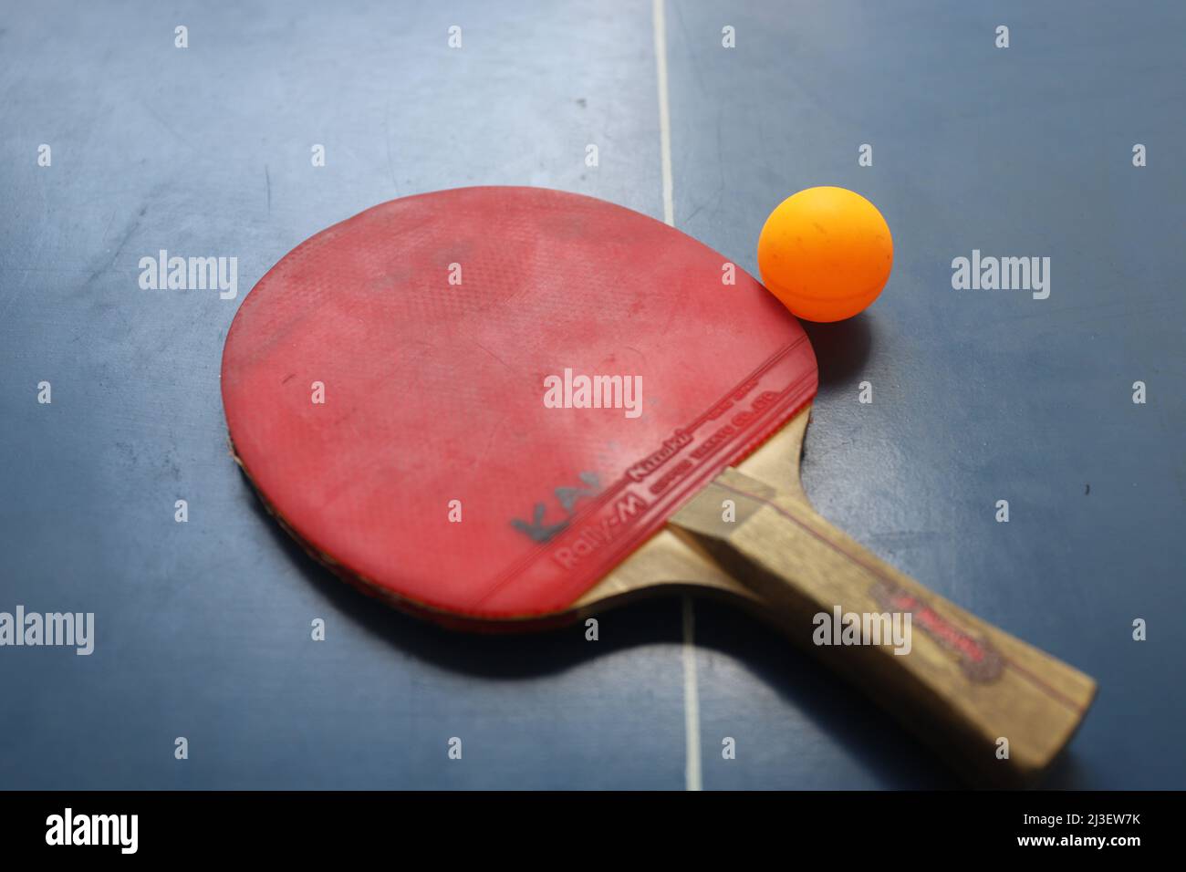 SURABAYA, INDONESIEN - 06. MÄRZ 2020: Zwei Tischtennis- oder Tischtennisschläger und -Kugeln auf einem blauen Tisch und Netz Stockfoto