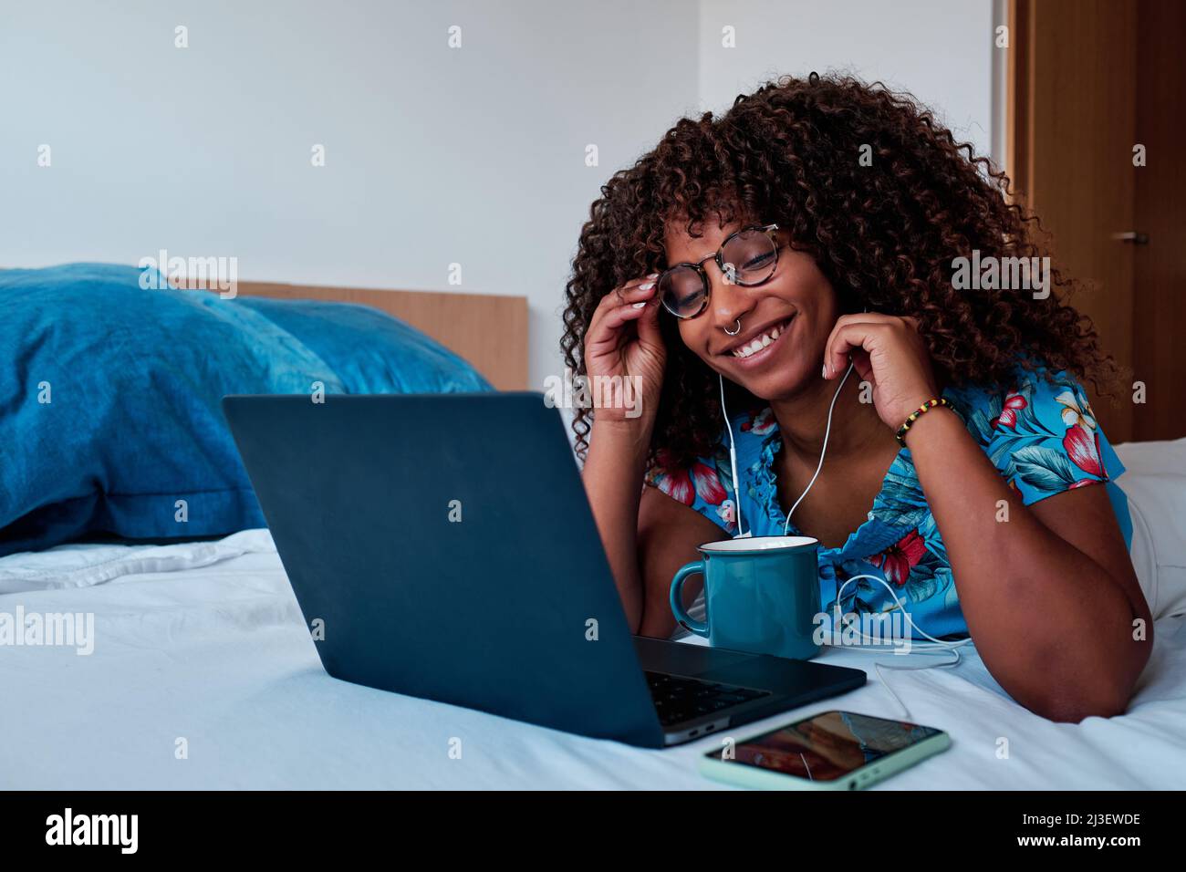 Junge afroamerikanische Frau im Bett, die zu Hause arbeitet Stockfoto