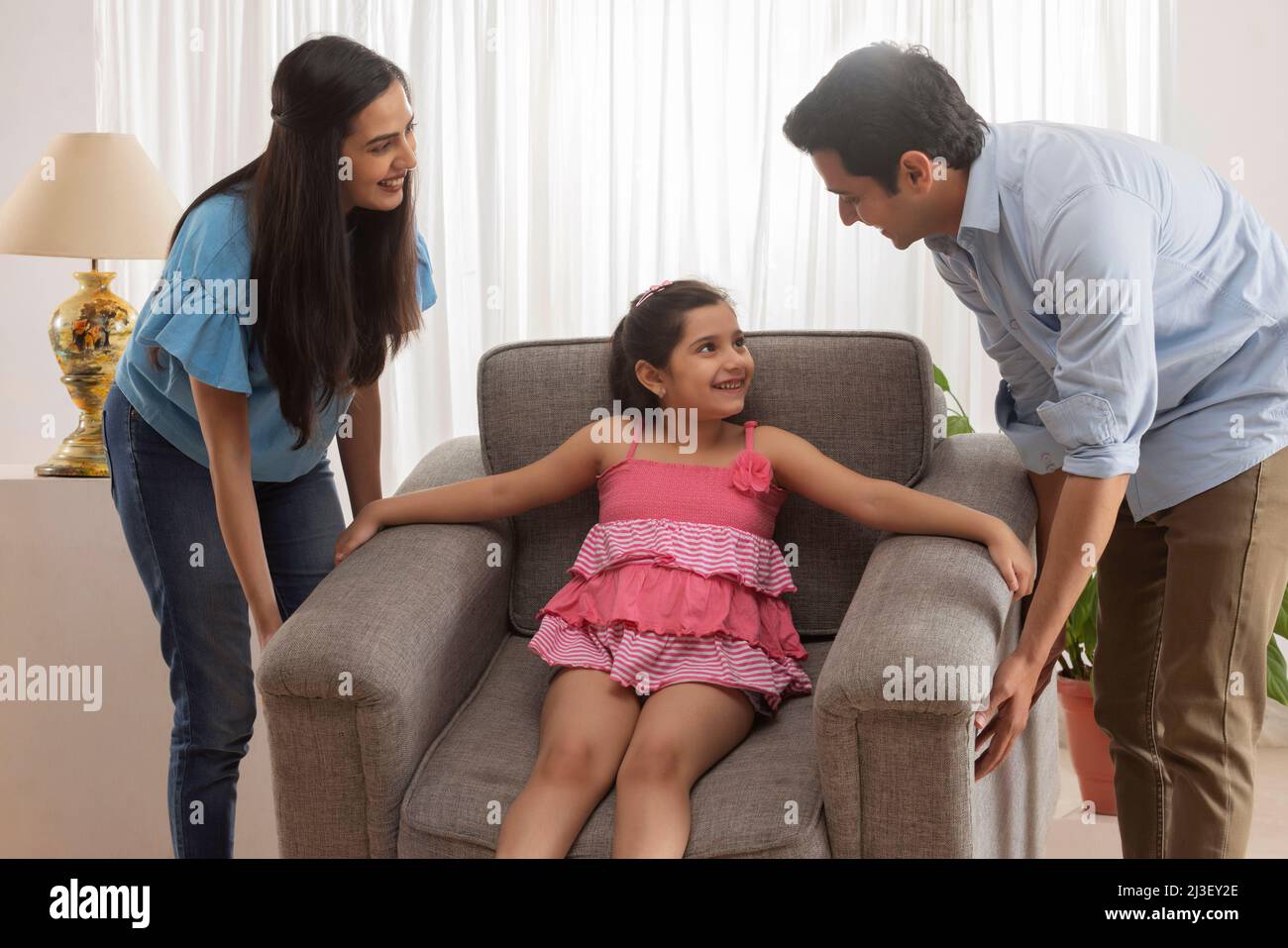 Eltern heben Sofa, während Tochter auf ihm sitzen Stockfoto