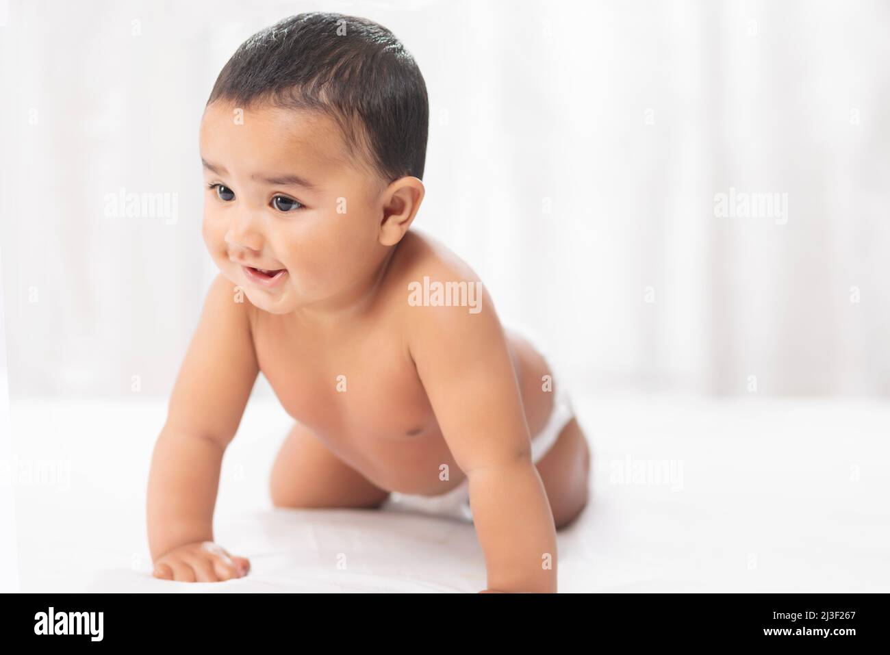 Niedliches Baby in Windel kriecht auf dem Bett Stockfoto