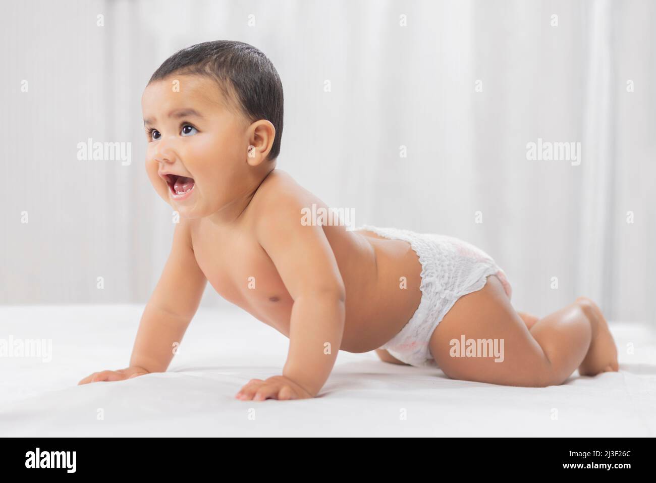 Niedliches Baby in Windel kriecht auf dem Bett Stockfoto