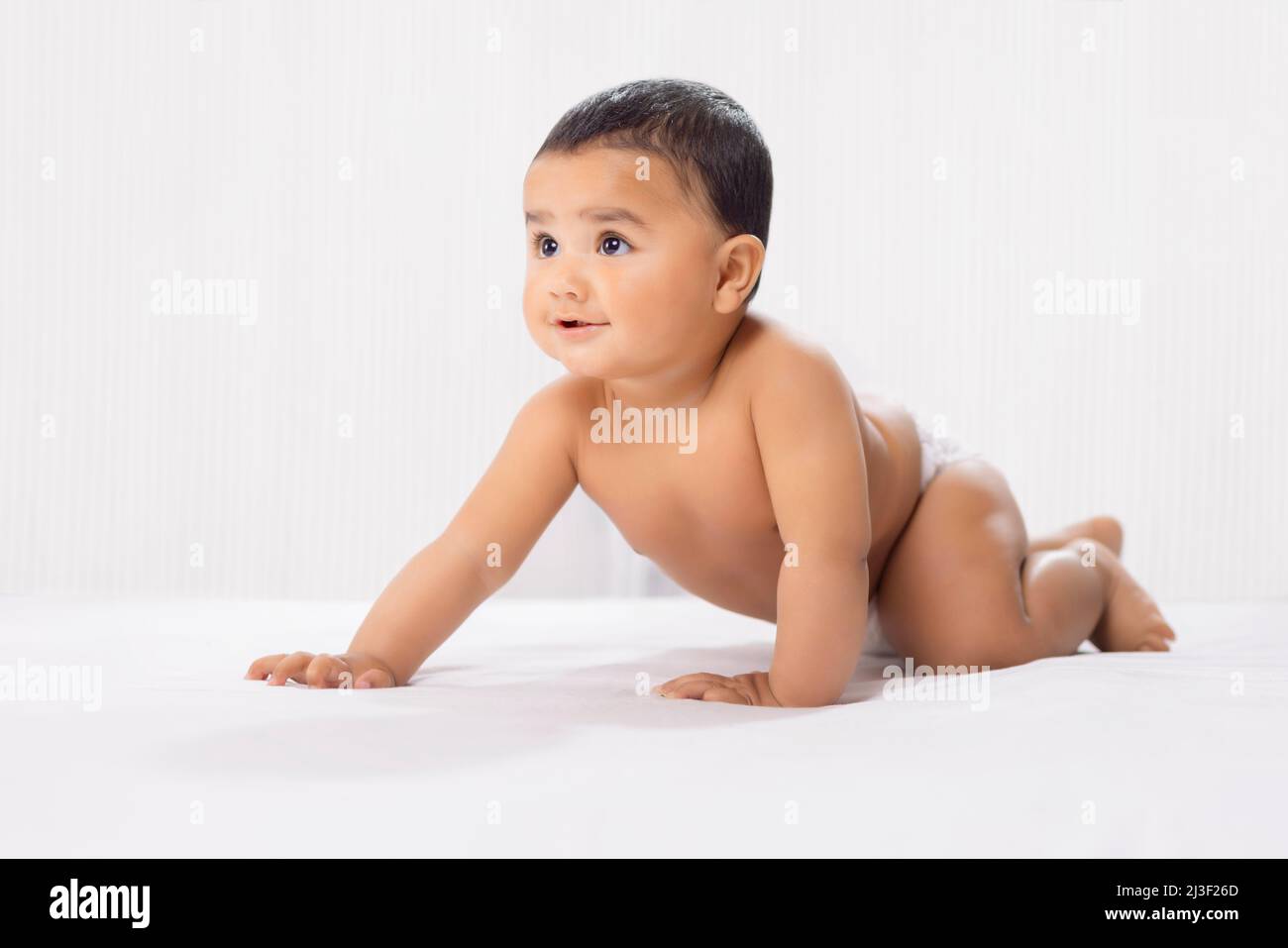 Niedliches Baby in Windel kriecht auf dem Bett Stockfoto