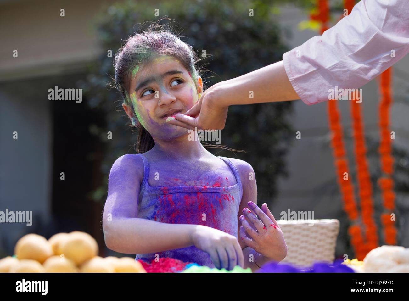 Jemand, der Farbe auf das Gesicht eines Mädchens auf Holi anwendet Stockfoto