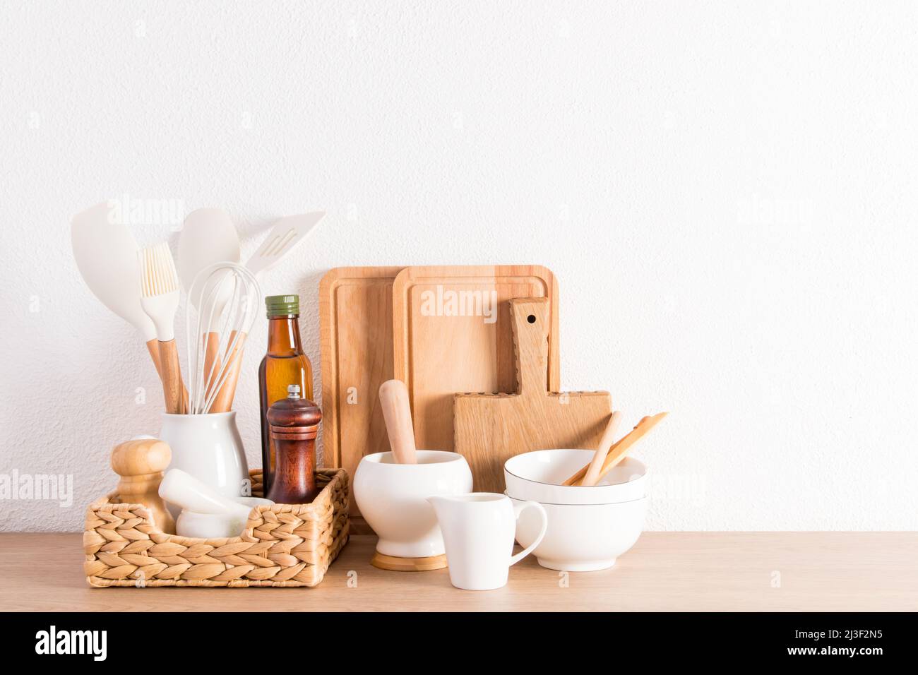Umweltfreundliche Artikel moderner Utensilien auf einer Küchenarbeitspe aus Holz in der Nähe einer weißen Strukturwand. Umweltfreundliche Materialien ohne Kunststoff Stockfoto