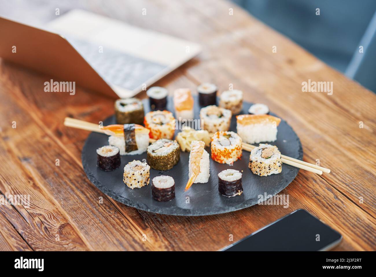 Steinplatte mit Sushi auf Holztisch Stockfoto