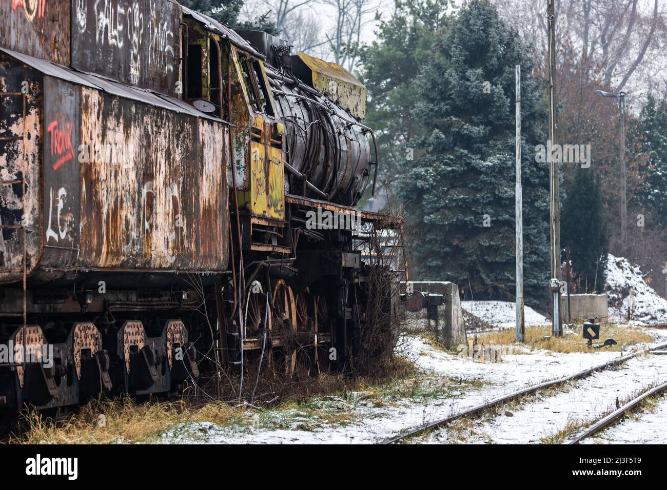 Alte, rostige, abgerissene Dampflokomotive, die auf der Seitenspur des Bahnhofs steht. Aufnahme an bewölktem Wintertag. Stockfoto