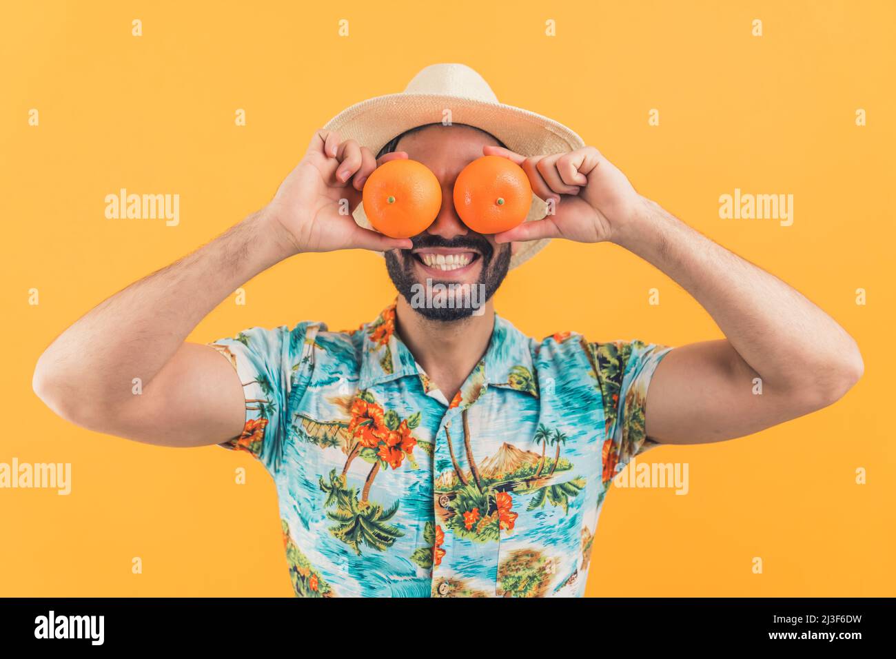 Junge attraktive lateinamerikanische Mann lachen und setzen Orangen auf die Augen Studio Schuss Medium closeup orange Hintergrund gesund Konzept. Hochwertige Fotos Stockfoto