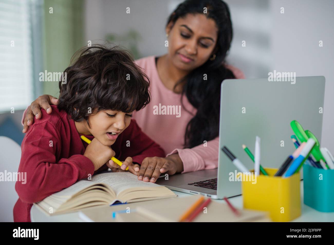 Indische Mutter mit kleinem Sohn mit Laptop und Online-Schulunterricht zu Hause. Stockfoto