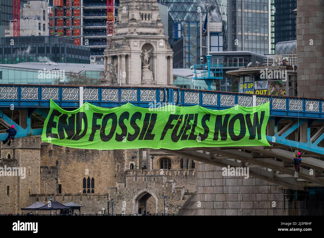 London, Großbritannien. 8. April 2022. Ende der fossilen Brennstoffe Jetzt - Aktivisten der Extinction Rebellion blockieren die Tower Bridge während der Hauptverkehrszeit und hängen ein Banner daran, das von zwei Rebellen, die ebenfalls unter der Brücke hängen, an Ort und Stelle gehalten wird. Kredit: Guy Bell/Alamy Live Nachrichten Stockfoto