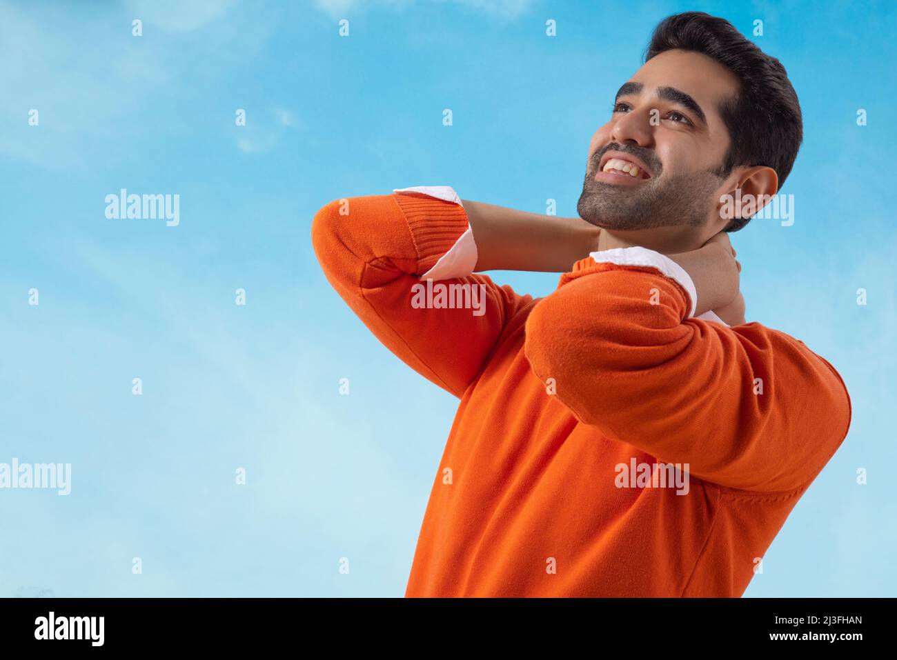 Glücklicher Mann, der unter dem blauen Himmel mit den Händen am Hals steht Stockfoto