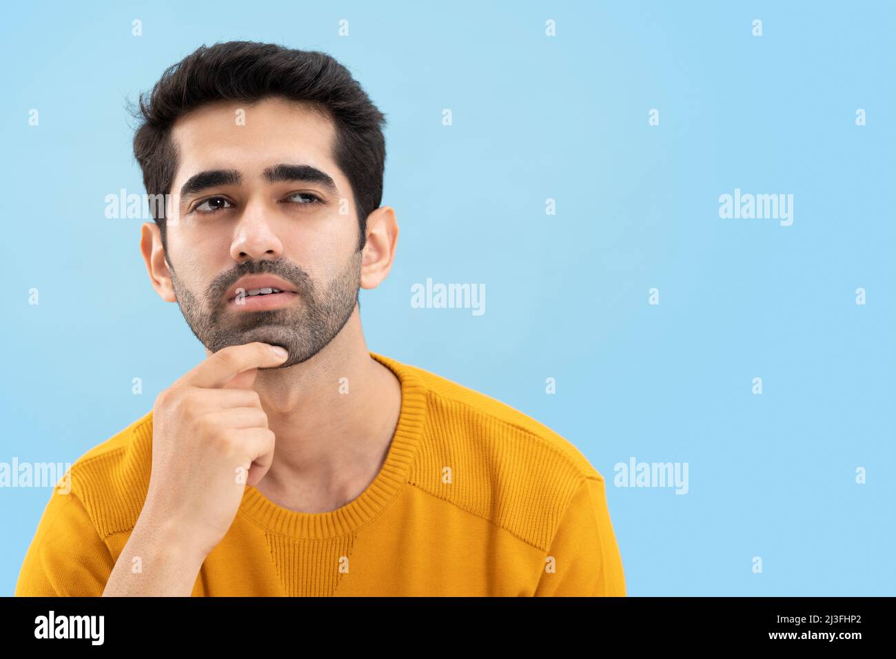 Porträt eines jungen Mannes, der wegschaut und mit der Hand auf dem Kinn denkt Stockfoto