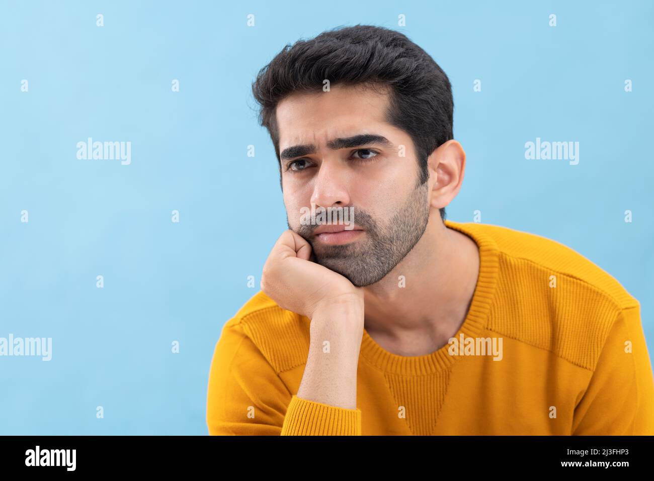 Porträt eines jungen Mannes, der wegschaut und mit der Hand auf dem Kinn denkt Stockfoto