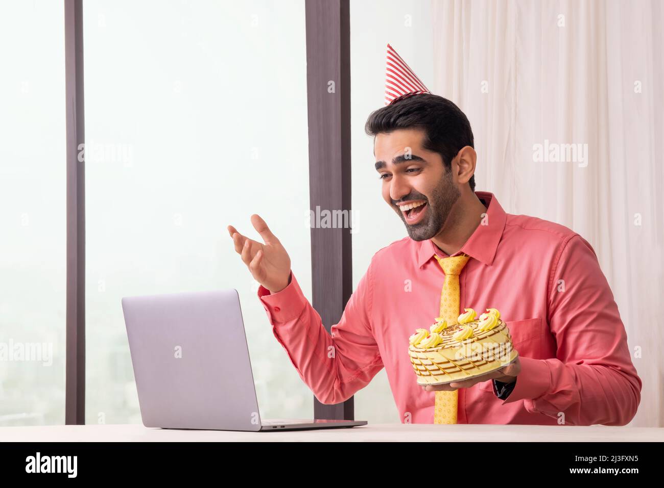 Glücklicher Firmenmann, der seinen Geburtstag durch Videoanruf feiert und mit Freunden im Büro chattet Stockfoto