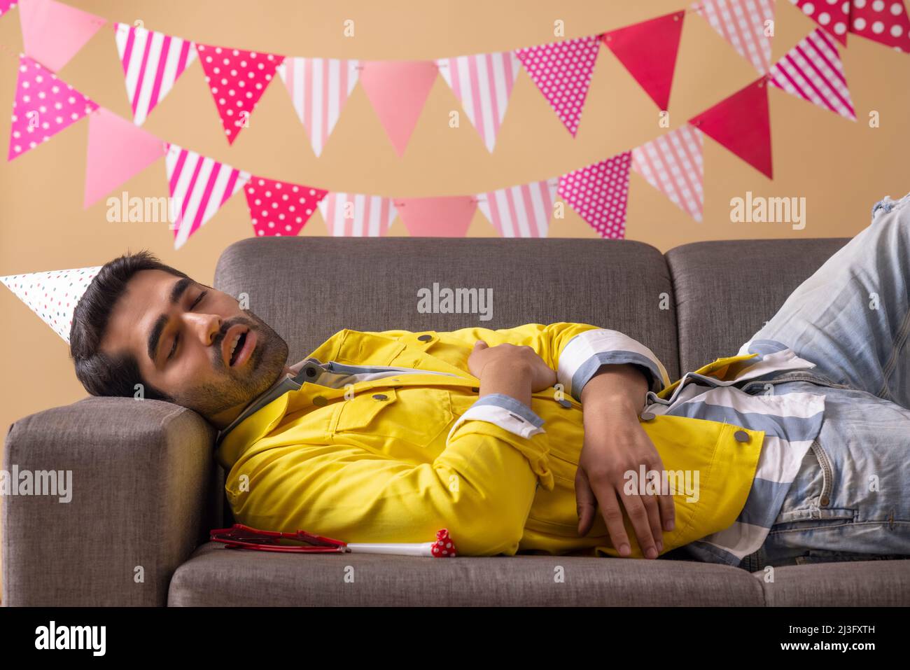 Junger Mann schläft auf dem Sofa, nachdem er auf der Party betrunken war Stockfoto