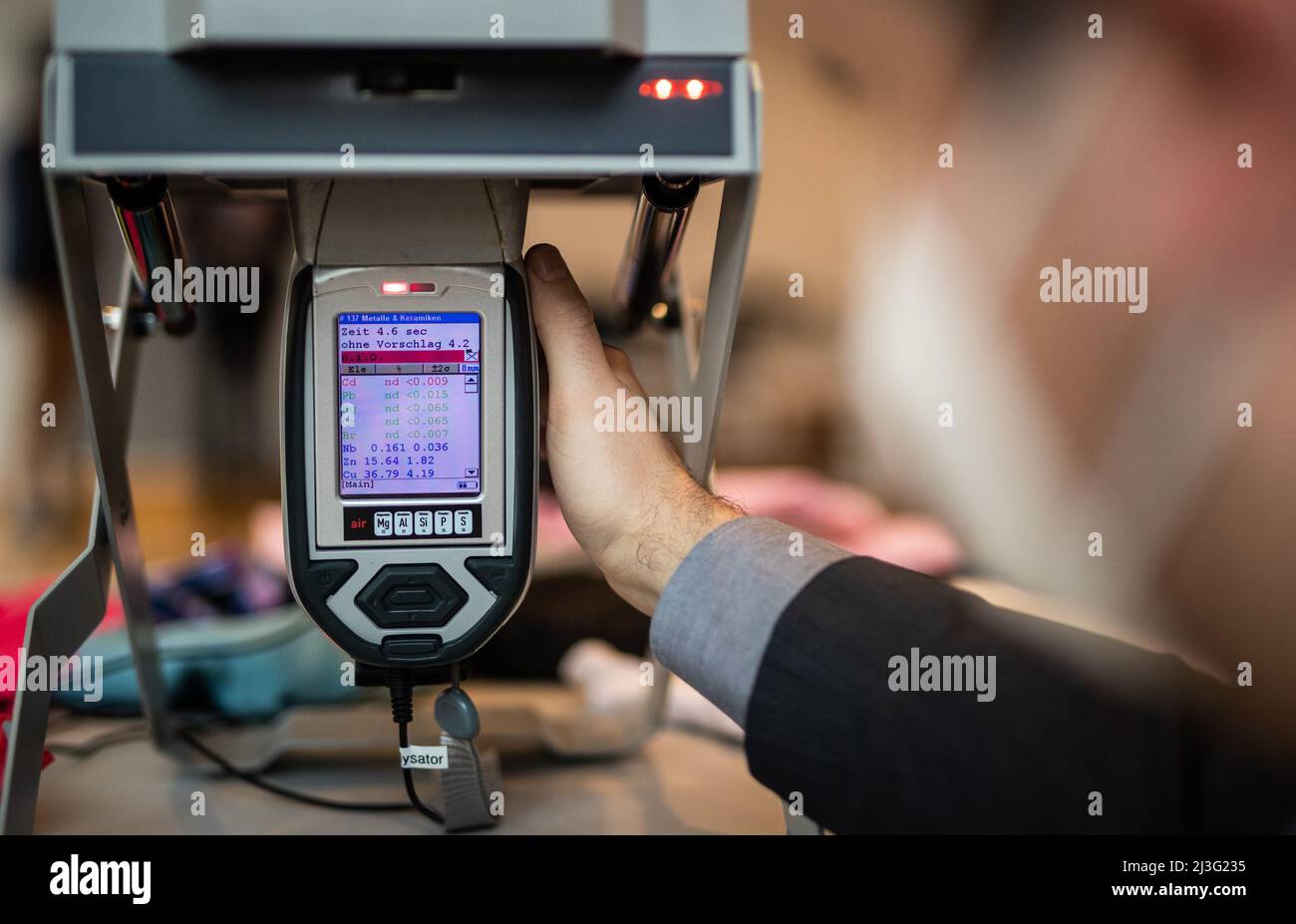 08. April 2022, Baden-Württemberg, Tübingen: Thorsten Haas, Mitarbeiter des Regierungspräsidium Tübingen, Abteilung Marktüberwachung Baden-Württemberg, untersucht mit Hilfe eines Analysegerätes einen Babytrampelanzug auf seine Inhaltsstoffe. Der Analysator, der mit Hilfe von Röntgenstrahlen arbeitet, zeigt die Inhaltsstoffe Cadmium (CD), Blei (Pb), Quecksilber (Hg), Chrom (Cr), Brom (Br), Niob (NB), Zink (Zn) und Kupfer (Cu) während der Elementanalyse. Foto: Christoph Schmidt/dpa Stockfoto