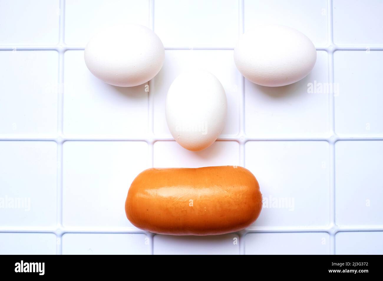 Eier und eine leckere Wurst auf einem weiß karierten Stand im Kühlschrank Stockfoto