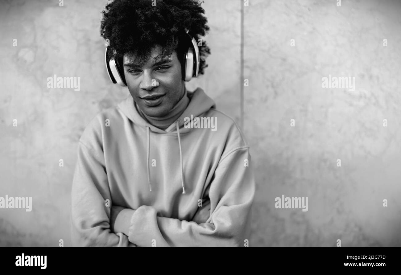 Fröhlicher Afro-Mann, der Musik mit kabellosen Kopfhörern im Freien hört – Lifestyle-Konzept der Millennial-Generation der Jugend Stockfoto