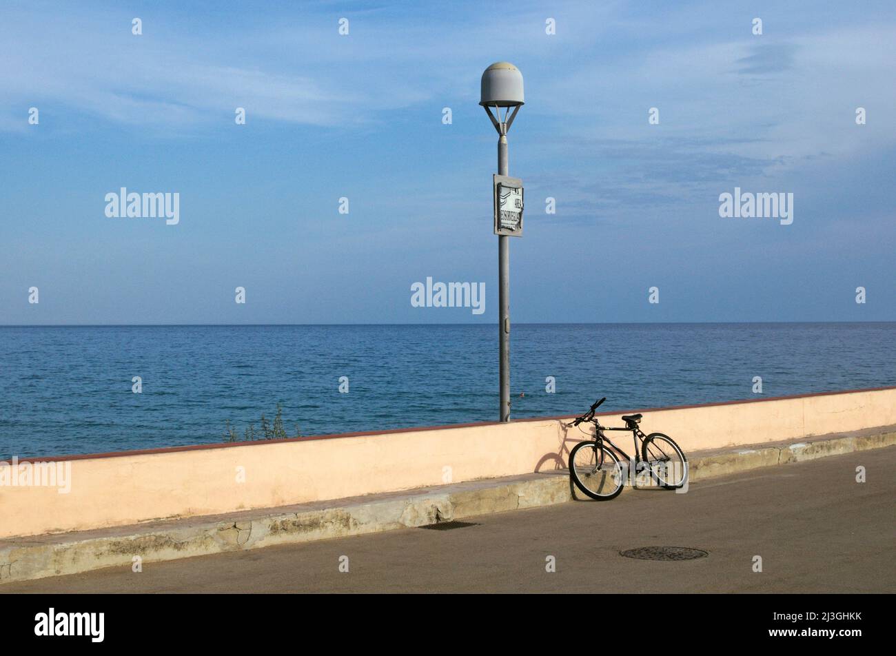 Fahrrad, das sich an einer Stützmauer am Meer lehnt, Finale Ligure, Ligurien, Italien Stockfoto