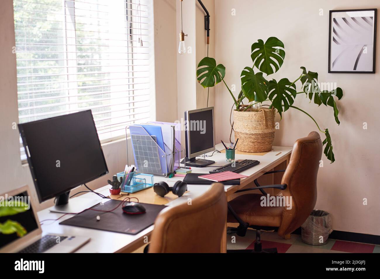 Eine Reihe leerer Schreibtische im Büro mit abgeschalteten Computern Stockfoto