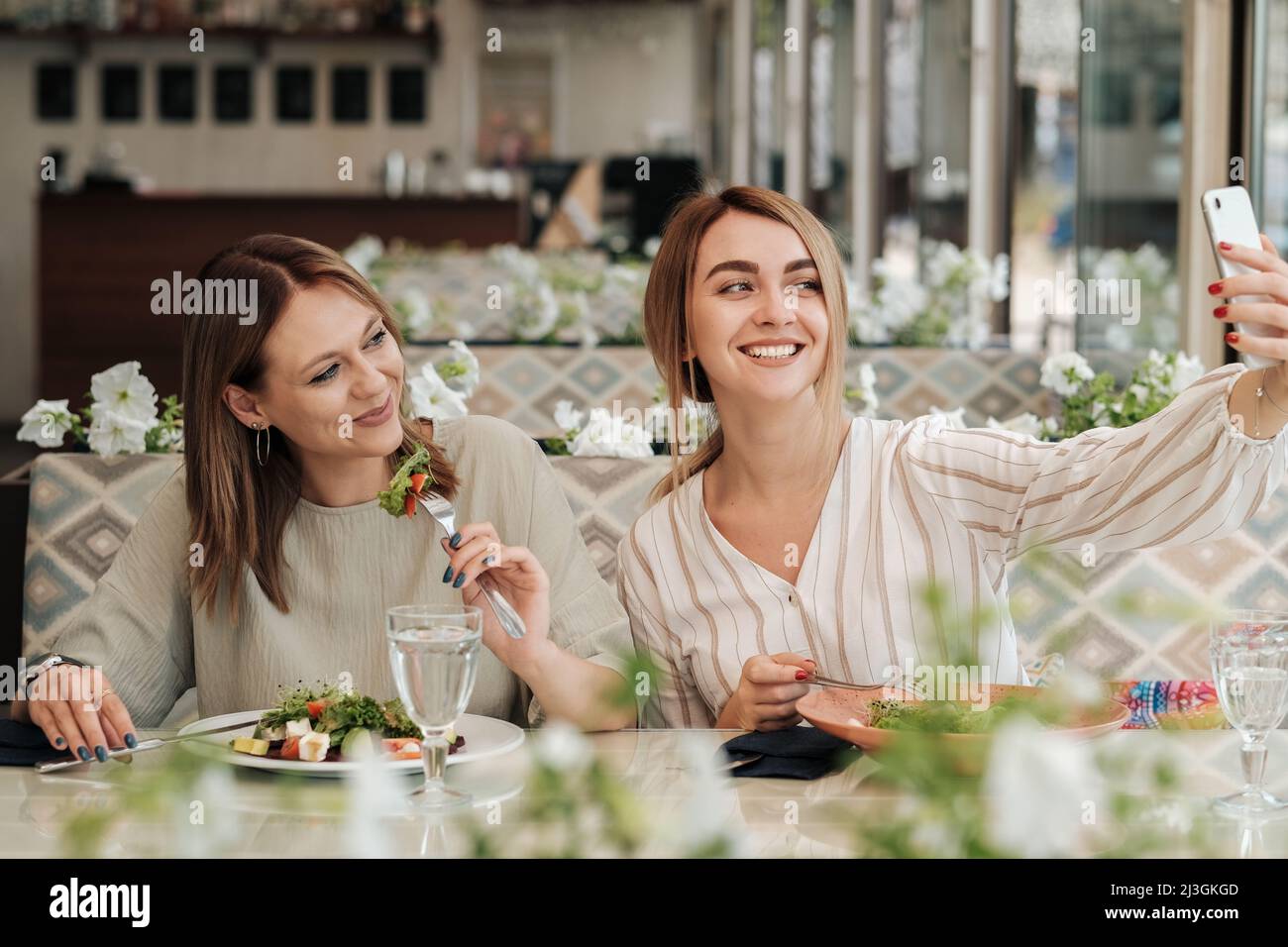 Zwei Frauen, die Selfie beim Mittagessen machen, weibliche Freunde, die Salat im Restaurant essen Stockfoto
