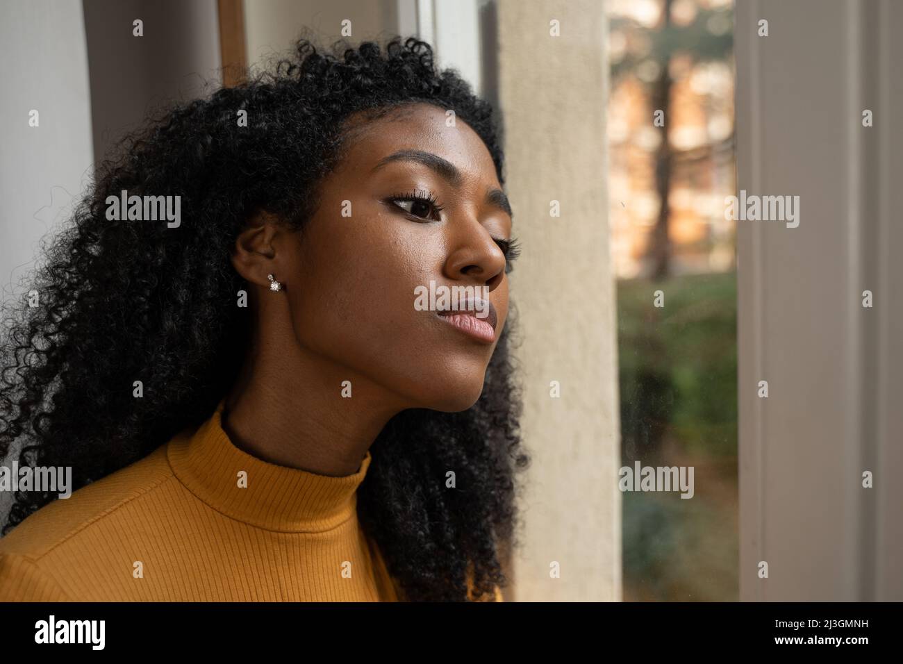 Eine schwarze Frau, die neugierig aus dem Fenster schaute Stockfoto